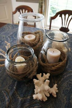 two glass vases filled with candles sitting on top of a table