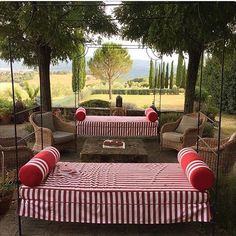 an outdoor seating area with red and white striped covers on the tables, couches and chairs