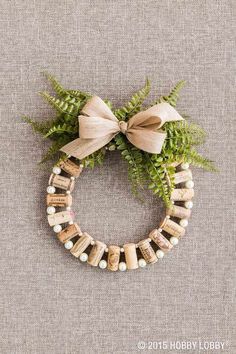 a wreath made out of wine corks and ferns with a bow on the front