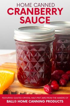 two jars filled with cranberry sauce sitting on top of a cutting board next to orange slices