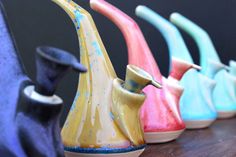 five ceramic vases are lined up on a table with one painted yellow, the other blue