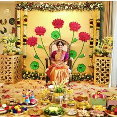 a woman sitting on a chair in front of a decorated stage with flowers and plates