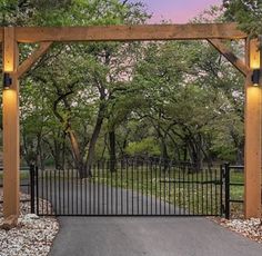 an open gate leading into a park with trees in the background