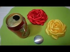 a can of soda and a rose on a green surface with a silver spoon next to it