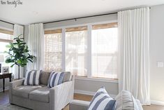 a living room filled with furniture and a large window covered in white drapes