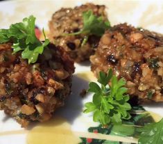 three meat patties on a plate with parsley garnished in sauce and seasoning