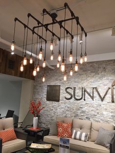 a living room filled with furniture and lots of light bulbs hanging from the ceiling above