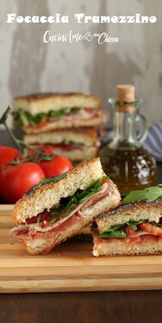 a cut in half sandwich sitting on top of a cutting board next to tomatoes and ketchup