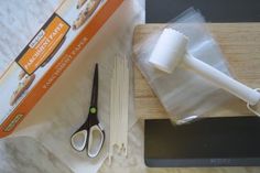 a pair of scissors sitting on top of a cutting board next to some food items