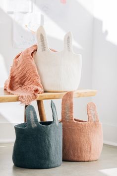 three different colored bags sitting on top of a wooden table in front of a window