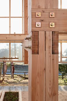 an open wooden door in the middle of a room with lots of windows and wood flooring