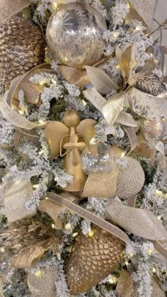 a christmas tree decorated with gold and silver ribbons, pine cones, ornaments and lights