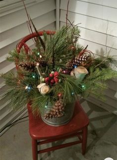 a christmas arrangement in a bucket on a chair