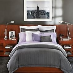 a bed with grey and purple comforter in a bedroom next to a painting on the wall