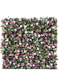 an artificial flower wall with pink and white flowers on the top, surrounded by greenery