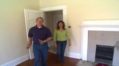 a man and woman standing in front of a fire place next to a doorway with an open door