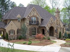 a large brick house with lots of windows and bushes around it's front entrance