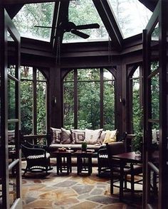 a living room filled with lots of furniture under a glass roof covered in wood and stone