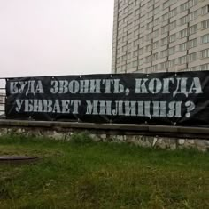 a large black sign on the side of a road in front of a tall building