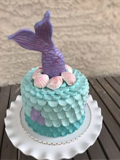 a blue and purple cake with a mermaid tail on top sitting on a white plate