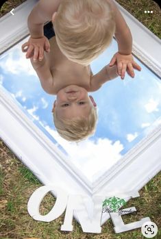 a toddler looking at himself in the mirror with his reflection on the ground next to it