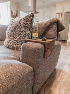 a bottle of whiskey sitting on top of a wooden table next to a couch in a living room