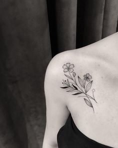 a black and white photo of a woman's shoulder with flowers tattooed on it