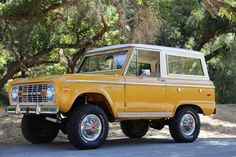 an orange truck parked on the side of a road next to some trees and bushes