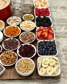 a table topped with bowls filled with different types of food next to fruit and nuts