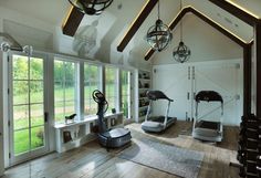 an exercise room with treadmills and other equipment in the center, along with large windows