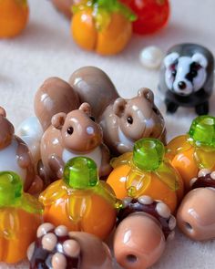 several small plastic animals sitting next to each other on a white tablecloth with oranges and green leaves