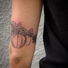 a woman's arm with a tattoo on it that has a pumpkin and leaves