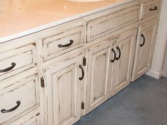 an old white bathroom vanity with black handles and knobs on the cabinet doors is shown