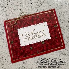 a christmas card with poinsettis and a merry message on the front, sitting on a marble surface