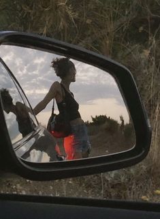 a woman is reflected in the side view mirror of a car's rear view mirror