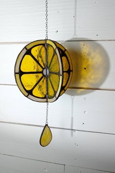 a stained glass lemon slice hanging from a chain on a white painted wood paneled wall