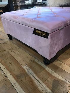 a purple ottoman sitting on top of a hard wood floor next to a white rug