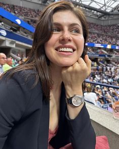 a woman sitting in the bleachers with her hand on her chin and looking at the camera