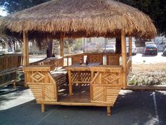 a wooden gazebo with thatched roof on the street