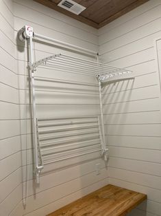 an empty room with a wooden bench and white painted walls in the corner, along with shelving