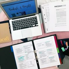 an open notebook sitting on top of a desk next to a laptop computer and other office supplies