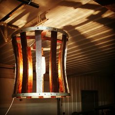 a light fixture made out of wood and metal with orange strips on the bottom, hanging from a ceiling