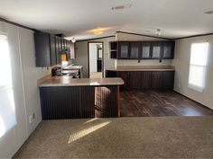 an empty kitchen and living room in a home with wood flooring, counter tops and cabinets