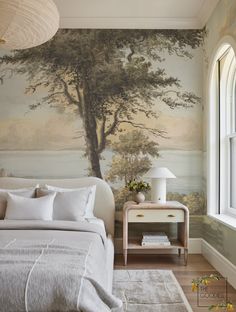 a bedroom with a tree mural on the wall next to a bed and night stand