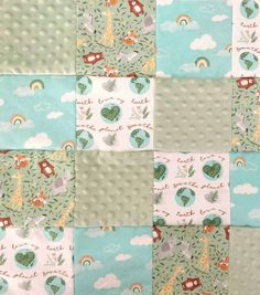 a patchwork quilt with animals, trees and clouds in pastel colors on it