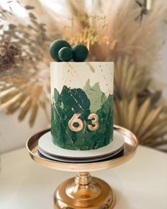 a green and white cake sitting on top of a gold plated platter next to plants