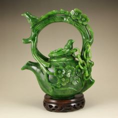 a green teapot with flowers and vines on it