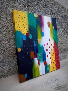 an abstract painting is displayed on a wall next to a cement wall and concrete floor