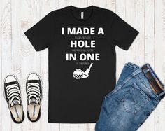 I Made A Hole In One Golf Shirt. Perfect as a golfing gift for both men and women. This classic unisex jersey short sleeve tee fits like a well-loved favorite. **Ladies - For unisex sizing: If you prefer a looser, casual fit order your normal size. If you prefer a slimmer fit, size down one** -Retail fit -100% Soft cotton - Heather colors are 52% Airlume combed and ring-spun cotton, 48% poly -Light fabric -Runs true to size Returns & Exchanges - I only accept returns & exchanges on cloth Black Golf T-shirt With Team Name, Sporty T-shirt With Team Name For Golf, Crew Neck T-shirt With Team Name For Golf, Cotton T-shirt With Letter Print For Golf, Pre-shrunk Short Sleeve Tops For Golf, Black Cotton T-shirt For Golf, Funny Golf Shirts, Funny Golf, Gifts For Golfers