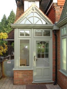 an orange brick house with a white glass door and side entry way leading to the outside